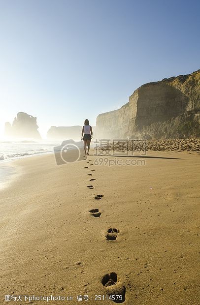 beach人白衬衫和黑色短裤漫步在蓝天白天虽然背后留下脚印