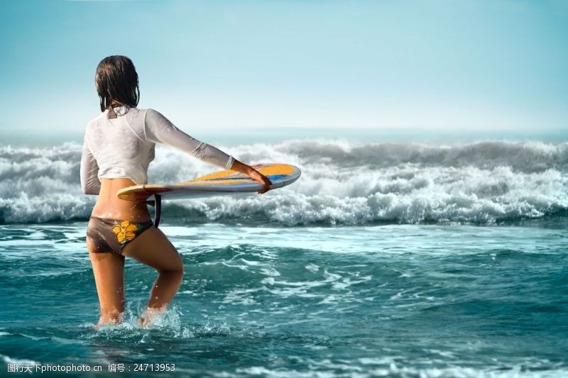 海上运动拿着冲浪板向海里走去的女人图片