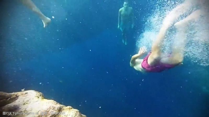 潜水运动清澈的水里来回游动的男女实拍视频